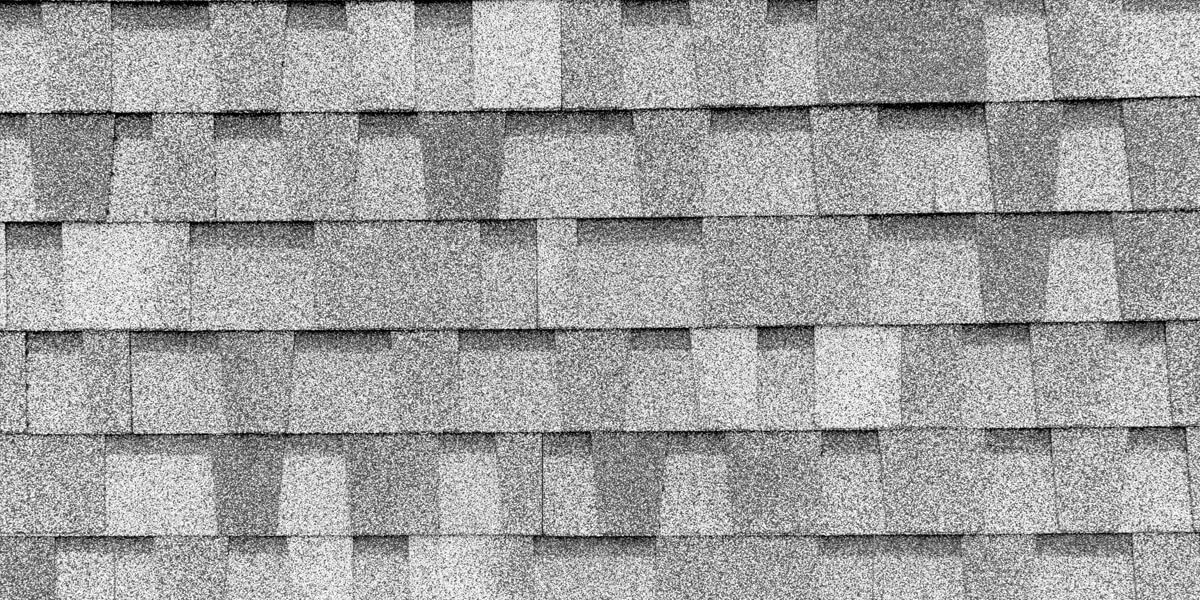 Close-up view of gray roof shingles for Orleans, arranged in a staggered overlapping pattern, highlighting the texture and subtle color variations across the surface.