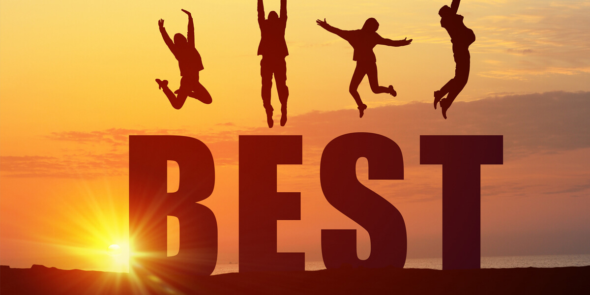 Four people jump joyfully on top of large letters spelling BEST with a vibrant orange sunset sky in the background, celebrating the achievement of being named best roofer in Ottawa.