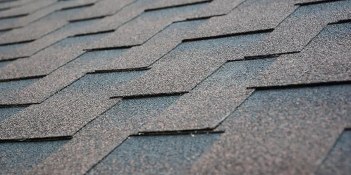 Close-up view of asphalt shingles Ottawa arranged in a staggered pattern on a rooftop, highlighting the textured, granulated surface and overlapping edges.