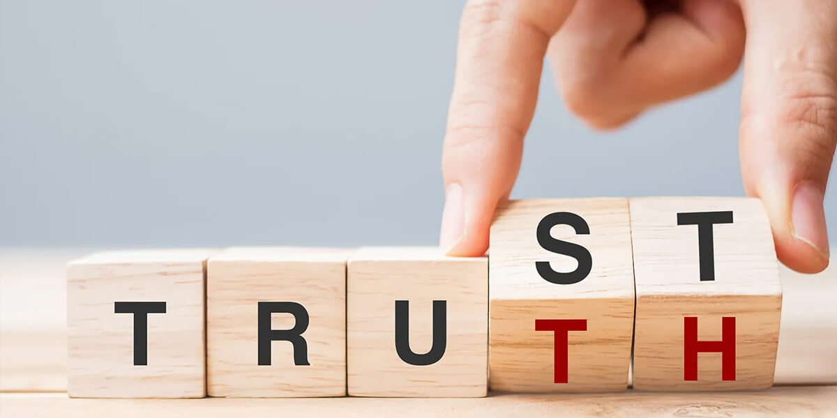 A hand flips a wooden block to change the word TRUST to TRUTH, symbolizing honest roofing in Ottawa, using black and red letters on a light wooden surface.