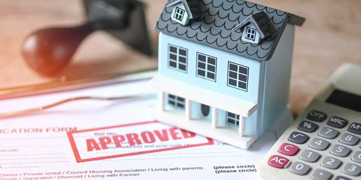 A small model house sits on top of mortgage documents with a large red APPROVED stamp, next to a calculator and pen, symbolizing home loan or roof replacement financing approval in Ottawa.