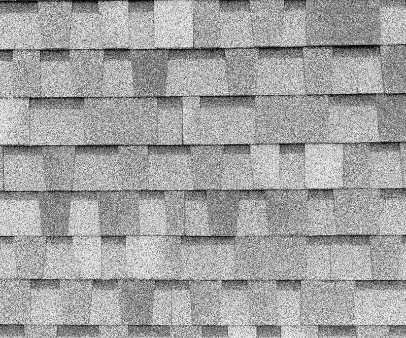 Close-up view of gray roof shingles for Orleans, arranged in a staggered overlapping pattern, highlighting the texture and subtle color variations across the surface.