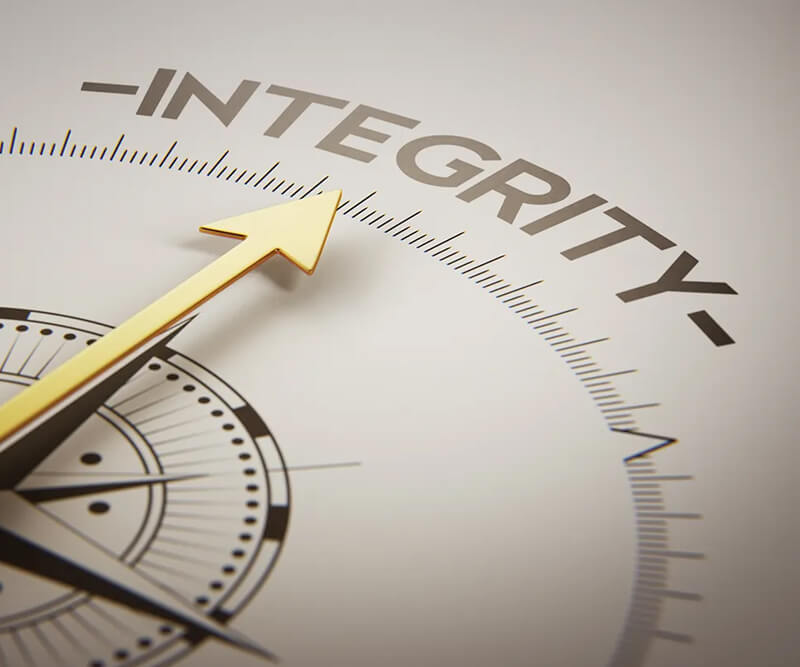 A close-up of a gold compass needle pointing toward the word INTEGRITY in bold letters, symbolizing guidance by strong moral principles—much like roofing integrity guides quality workmanship.