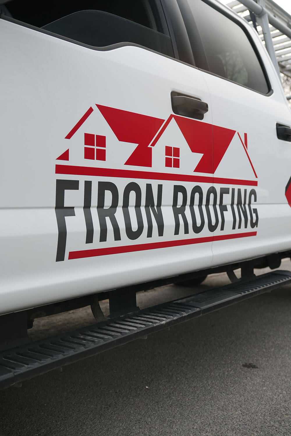 A white truck with a Firon Roofing logo on the door, featuring red rooftops and bold black and red lettering, parked on a paved surface—proudly serving Ottawa / Gatineau.